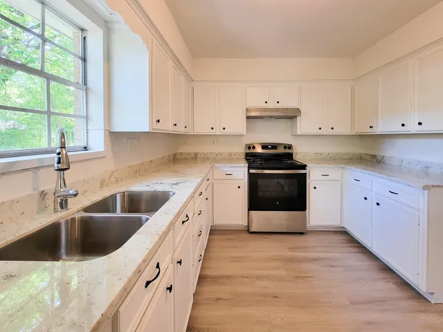 a kitchen with granite countertop a stove sink and cabinets
