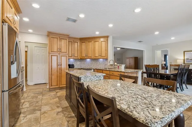 a kitchen with stainless steel appliances granite countertop table chairs sink refrigerator and microwave