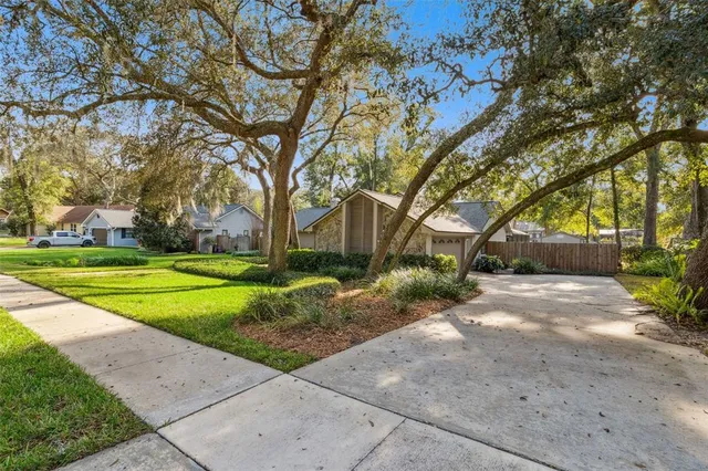 a view of a house with a big yard and large trees