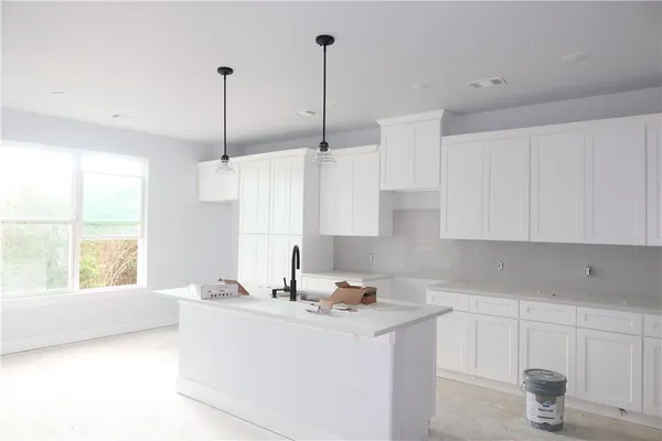 a kitchen with stainless steel appliances granite countertop a sink a window and white cabinets