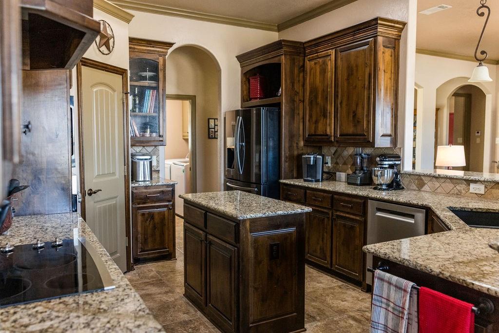 123 Cactus Drive Decatur, TX 76234 - Photo 11 of 30 Kitchen featuring rich wood cabinetry, granite countertops, tile backsplash, and a central island