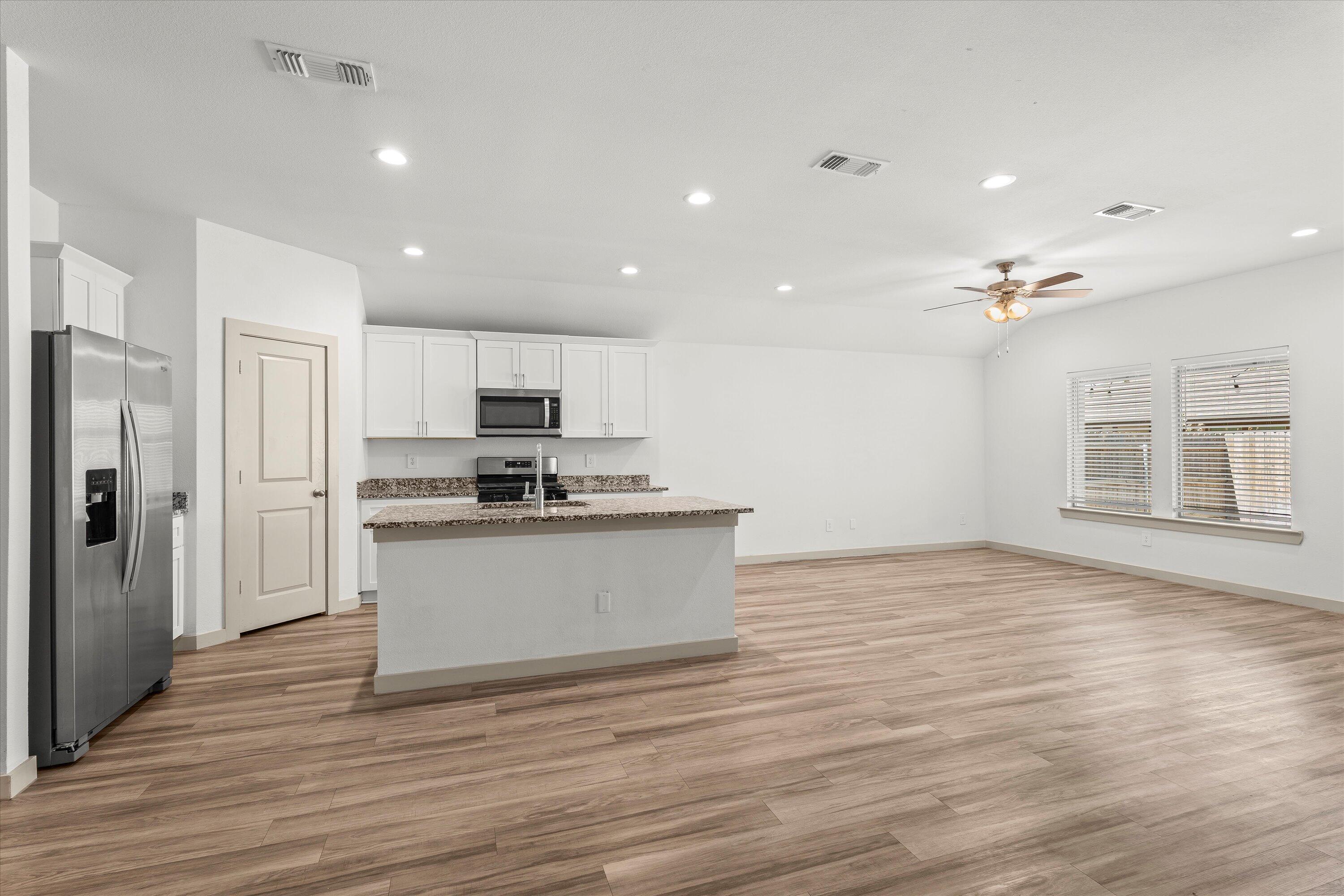 7416 9th Street Lubbock, TX 79416 - Photo 12 of 34 a view of kitchen with stainless steel appliances granite countertop a stove top oven a refrigerator and white cabinets with wooden floor