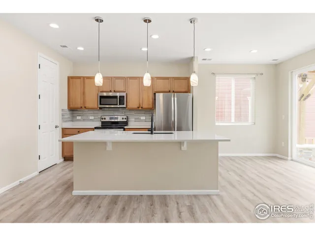 a kitchen with stainless steel appliances granite countertop a refrigerator a sink a stove and a wooden floors