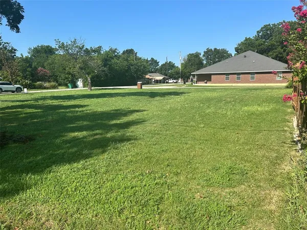 a swimming pool is sitting in the grass with large trees and sky view