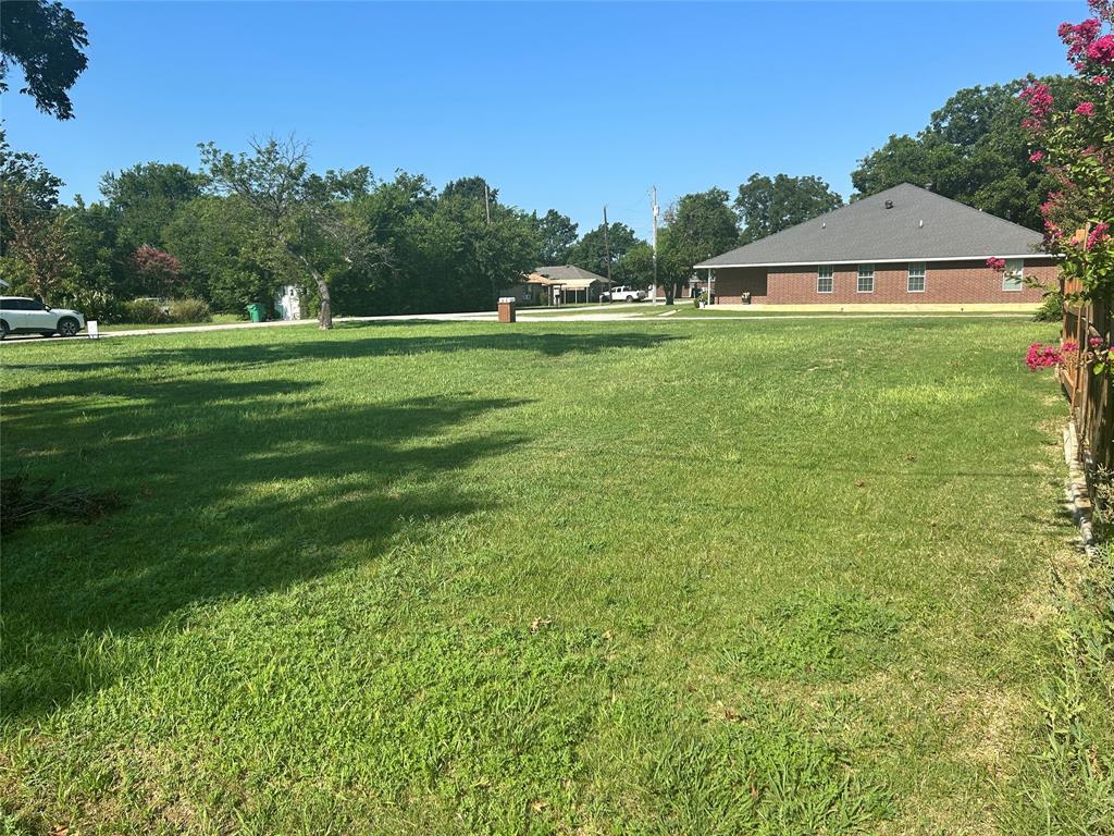 a swimming pool is sitting in the grass with large trees and sky view