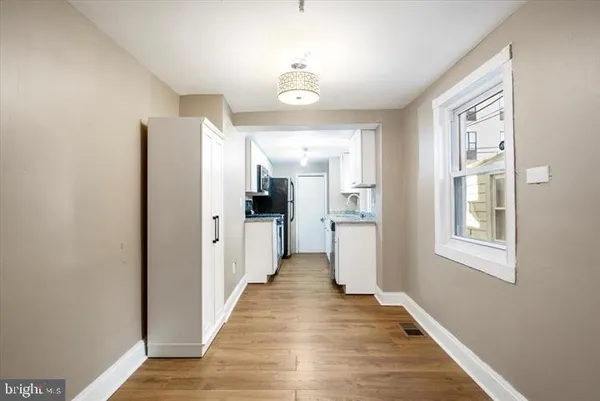 a view of a hallway with wooden floor and a living room