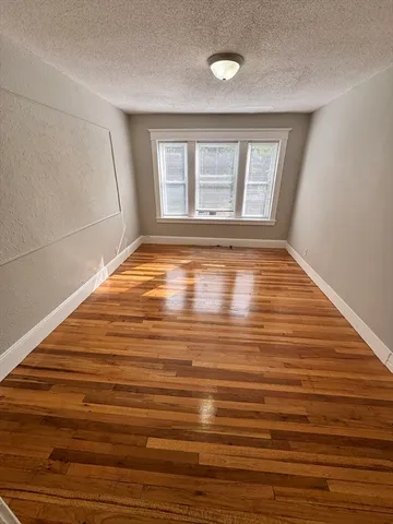 a view of empty room with window and wooden floor