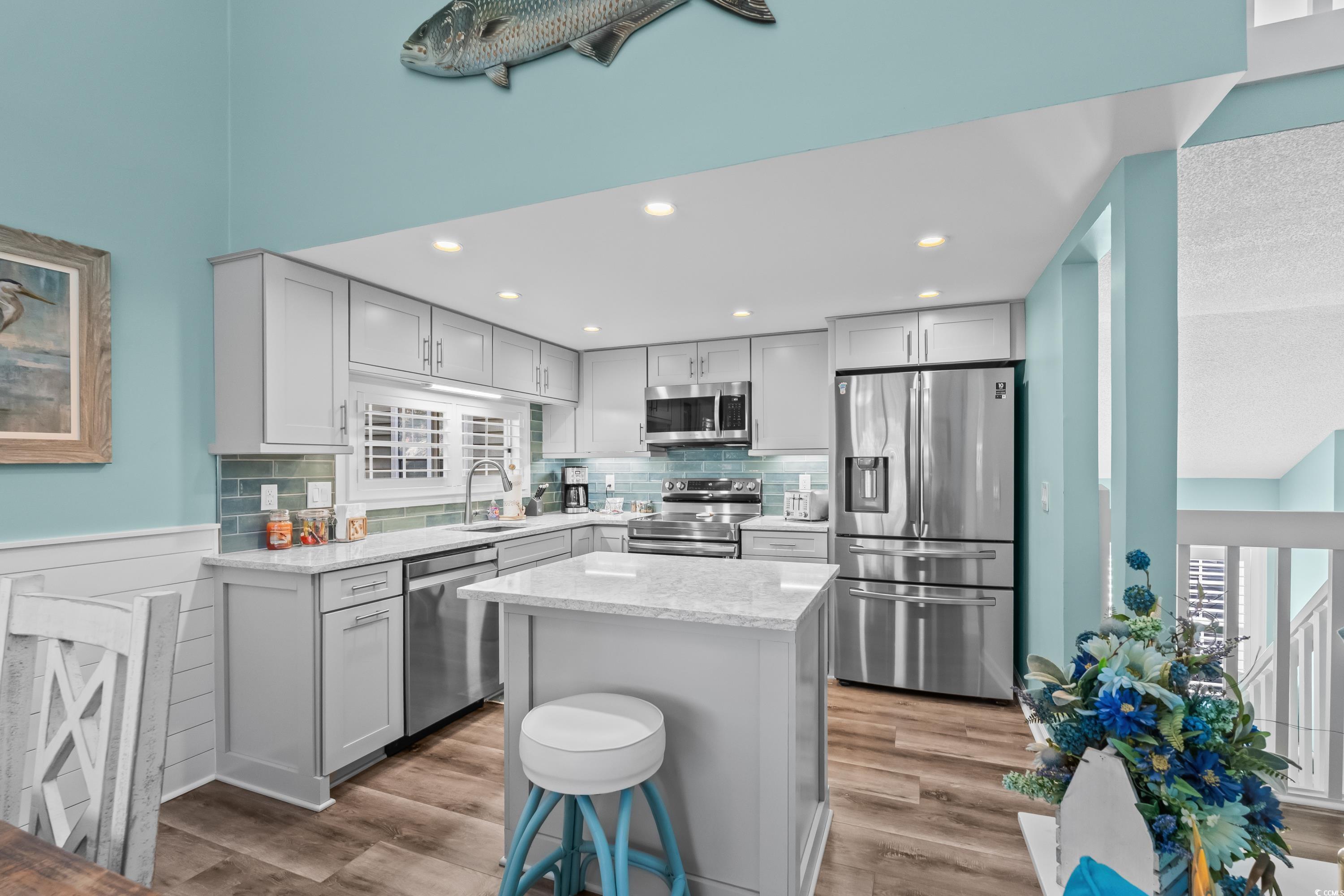 304 Cumberland Terrace, Unit 2F Myrtle Beach, SC 29572 - Photo 11 of 40 Kitchen with stainless steel appliances, light stone counters, light wood-type flooring, and backsplash