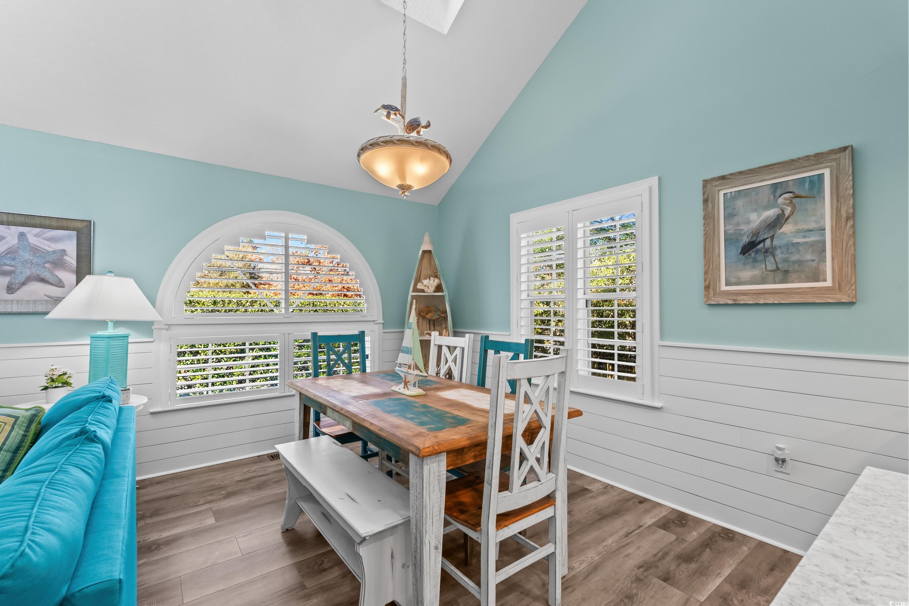304 Cumberland Terrace, Unit 2F Myrtle Beach, SC 29572 - Photo 16 of 40 Dining room with wainscoting, a skylight, wood finished floors, and high vaulted ceiling