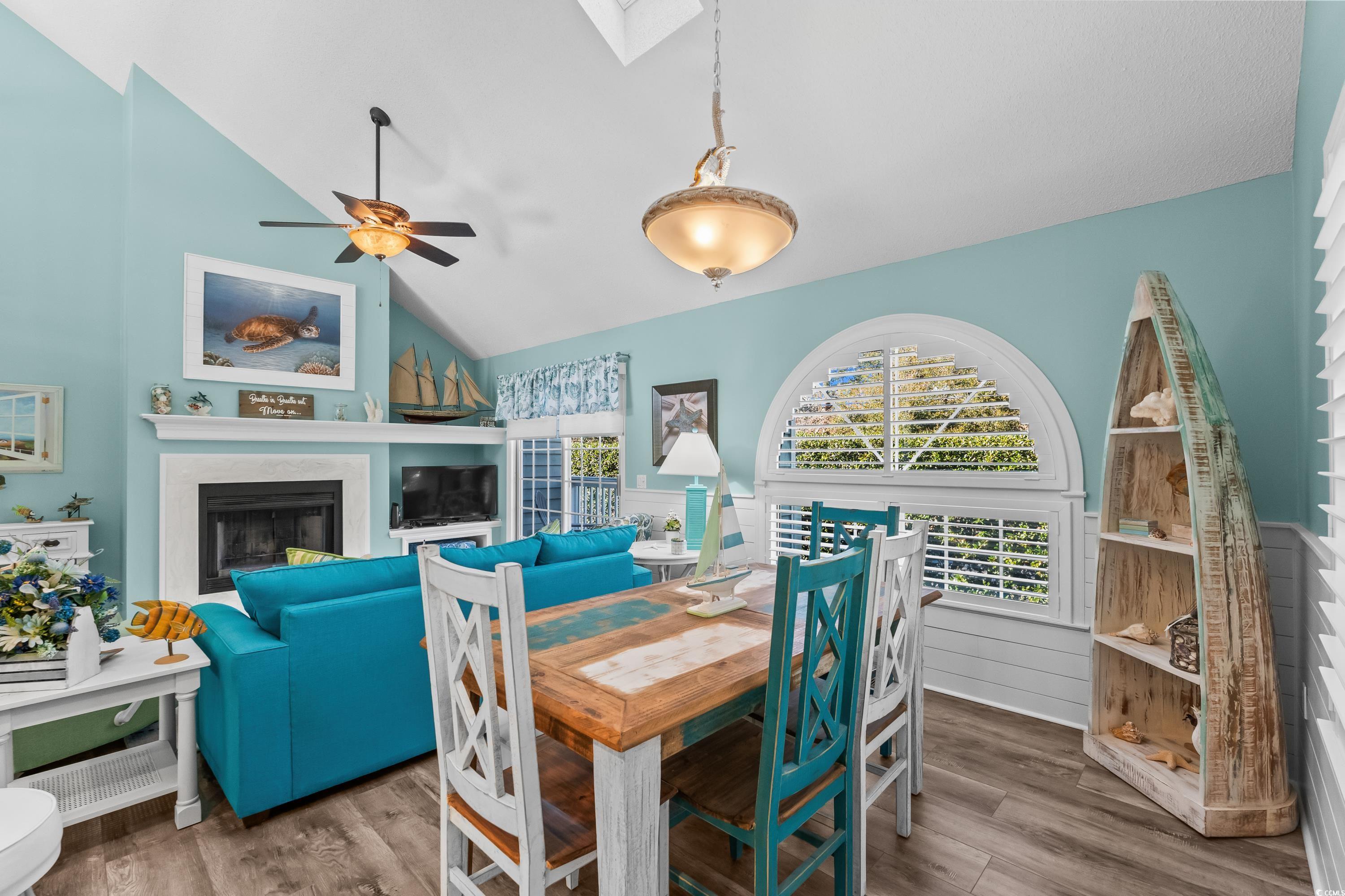 304 Cumberland Terrace, Unit 2F Myrtle Beach, SC 29572 - Photo 17 of 40 Dining room featuring a skylight, a fireplace, a wainscoted wall, wood finished floors, and vaulted ceiling