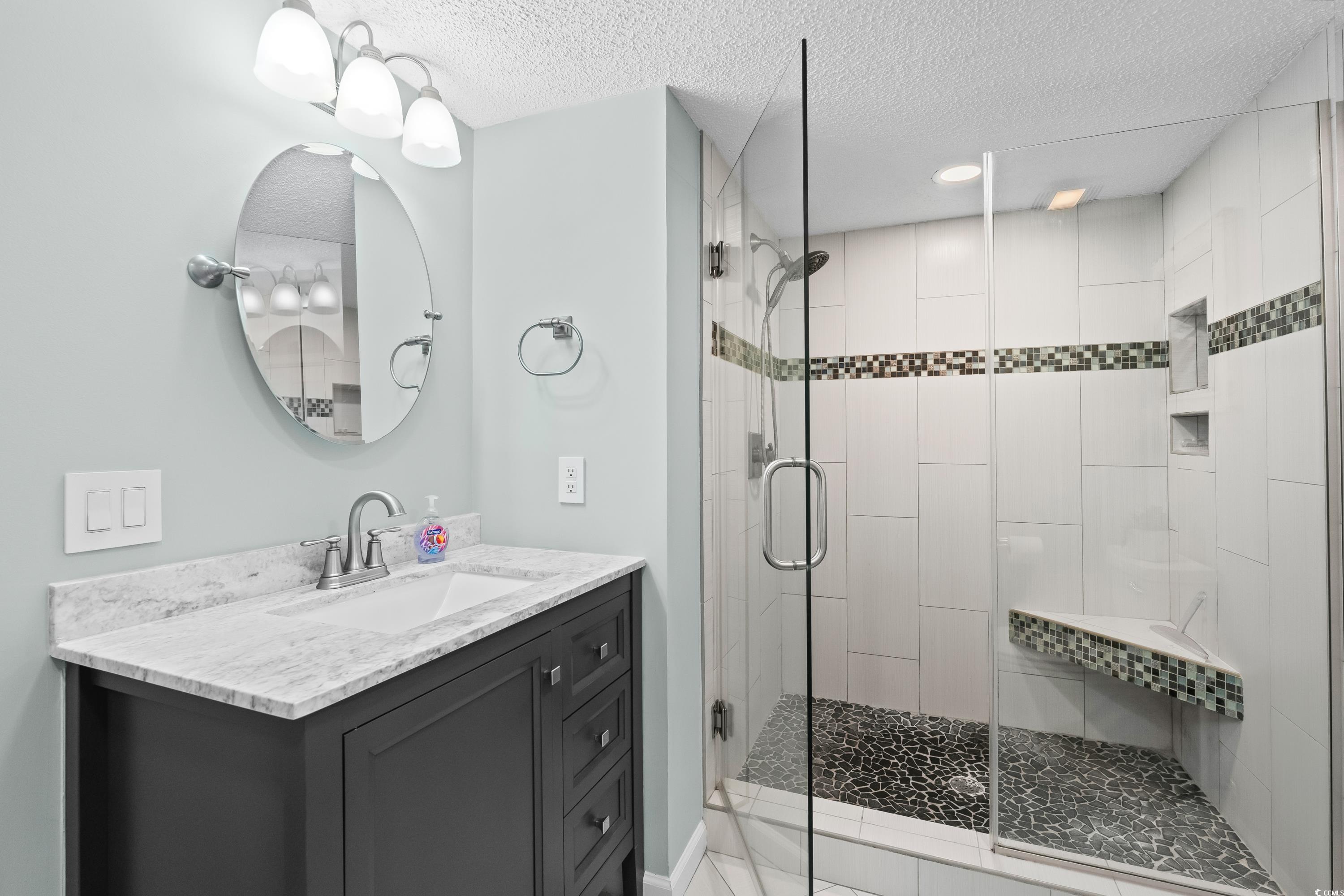 304 Cumberland Terrace, Unit 2F Myrtle Beach, SC 29572 - Photo 25 of 40 Bathroom featuring vanity, a shower stall, and a textured ceiling