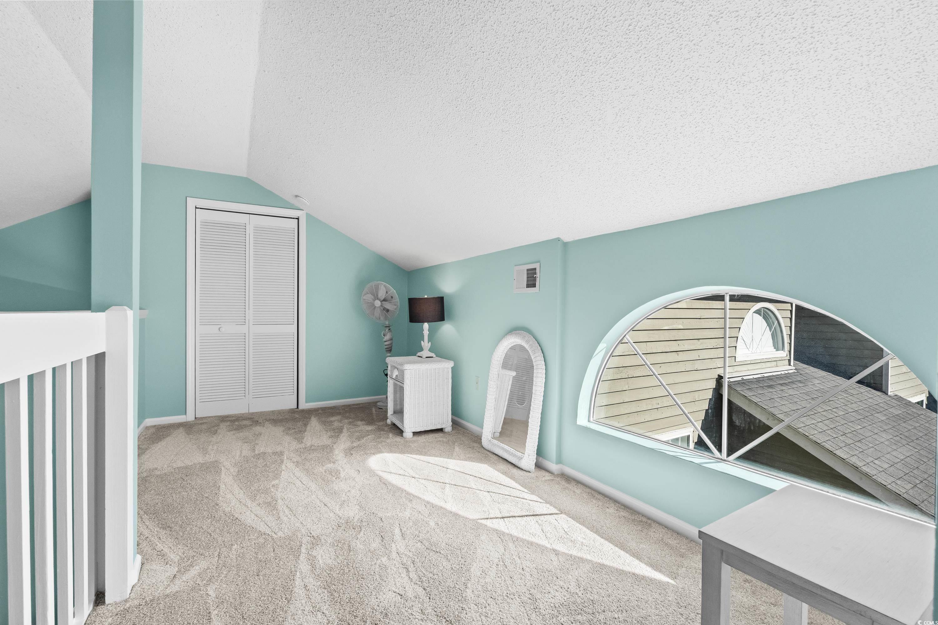 304 Cumberland Terrace, Unit 2F Myrtle Beach, SC 29572 - Photo 31 of 40 Additional living space with vaulted ceiling, carpet floors, and a textured ceiling