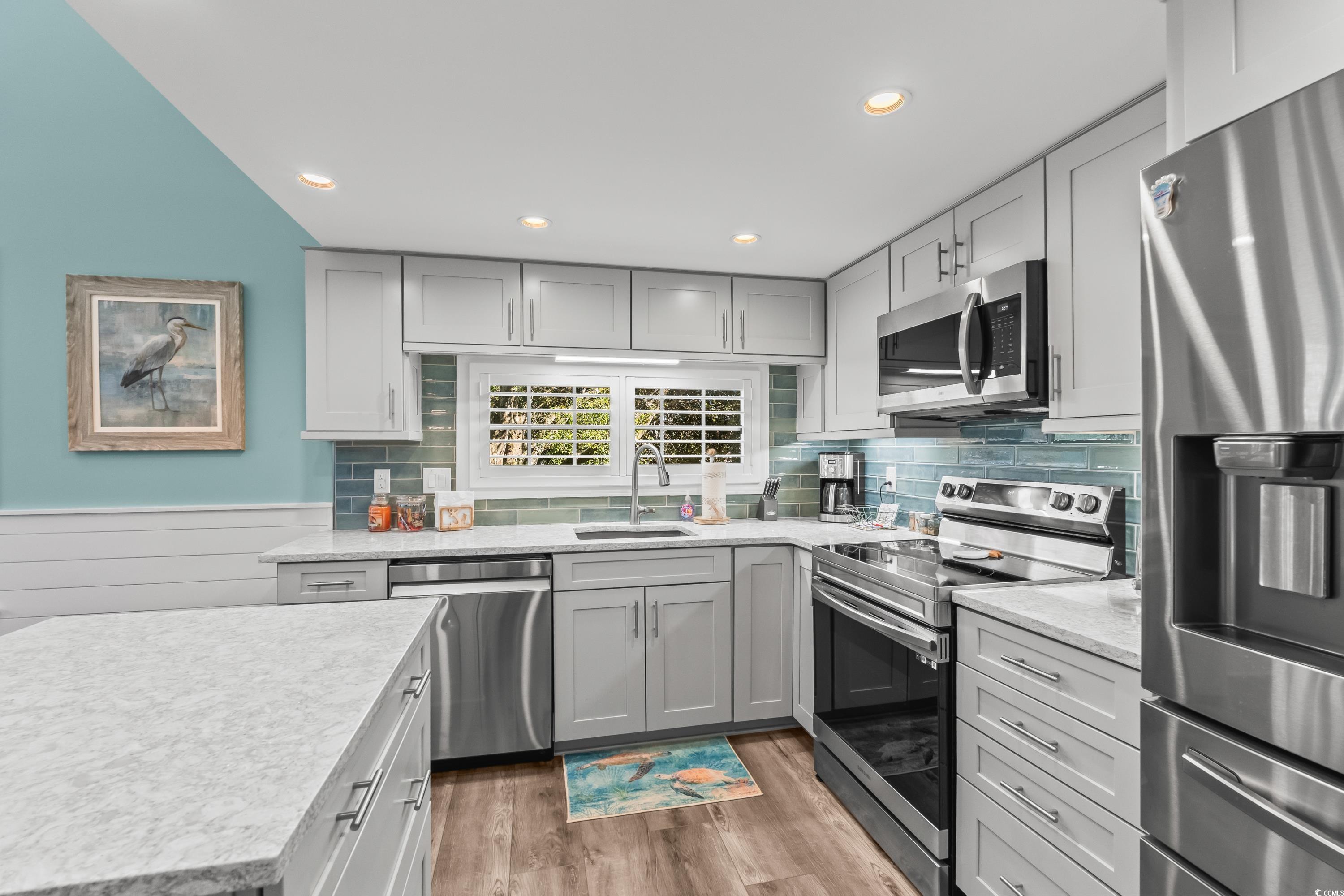 304 Cumberland Terrace, Unit 2F Myrtle Beach, SC 29572 - Photo 4 of 40 Kitchen with appliances with stainless steel finishes, gray cabinets, light wood-type flooring, tasteful backsplash, and recessed lighting