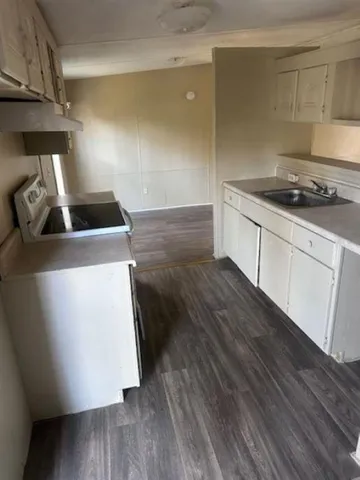 a kitchen with wooden floor sink and stove