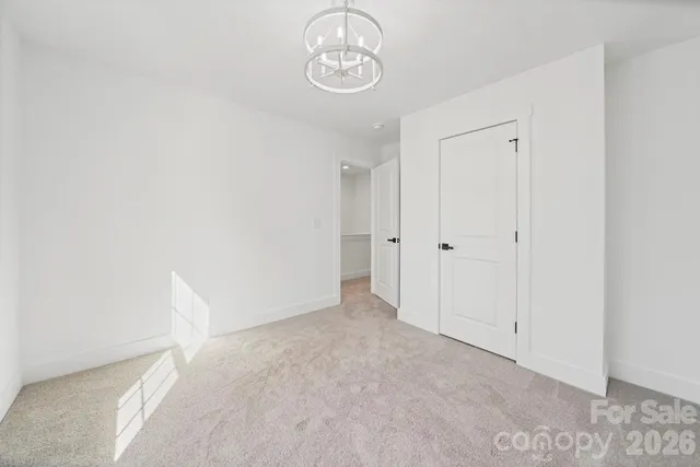 a view of an empty room with chandelier fan