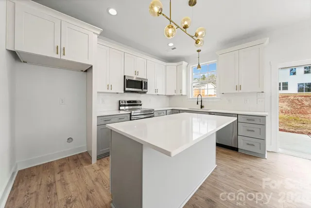 a kitchen with kitchen island a sink appliances cabinets and a counter top space