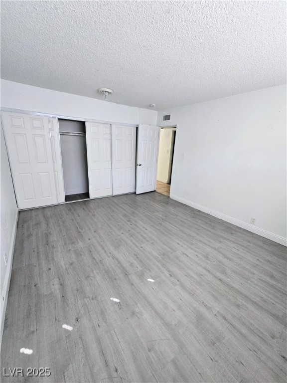 908 North Jones Boulevard, Unit B Las Vegas, NV 89108 - Photo 21 of 28 Unfurnished bedroom featuring light wood-style floors, a textured ceiling, and a closet