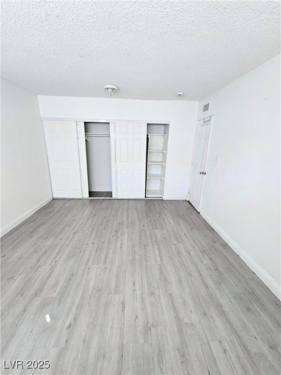 908 North Jones Boulevard, Unit B Las Vegas, NV 89108 - Photo 24 of 28 Unfurnished bedroom featuring a textured ceiling, light wood finished floors, and a closet