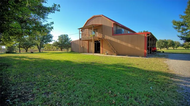 a view of a big house with a big yard and large trees