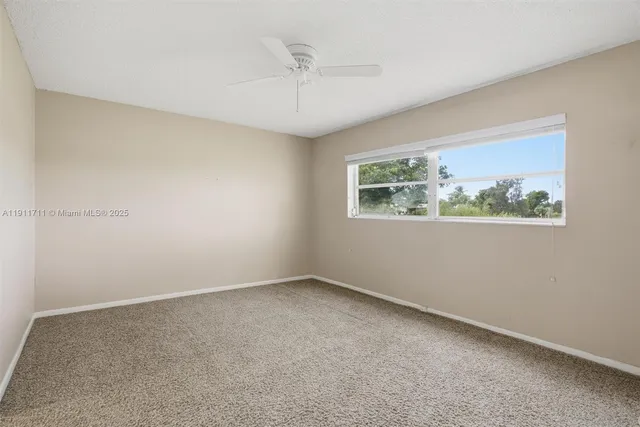 an empty room with a window and a ceiling fan