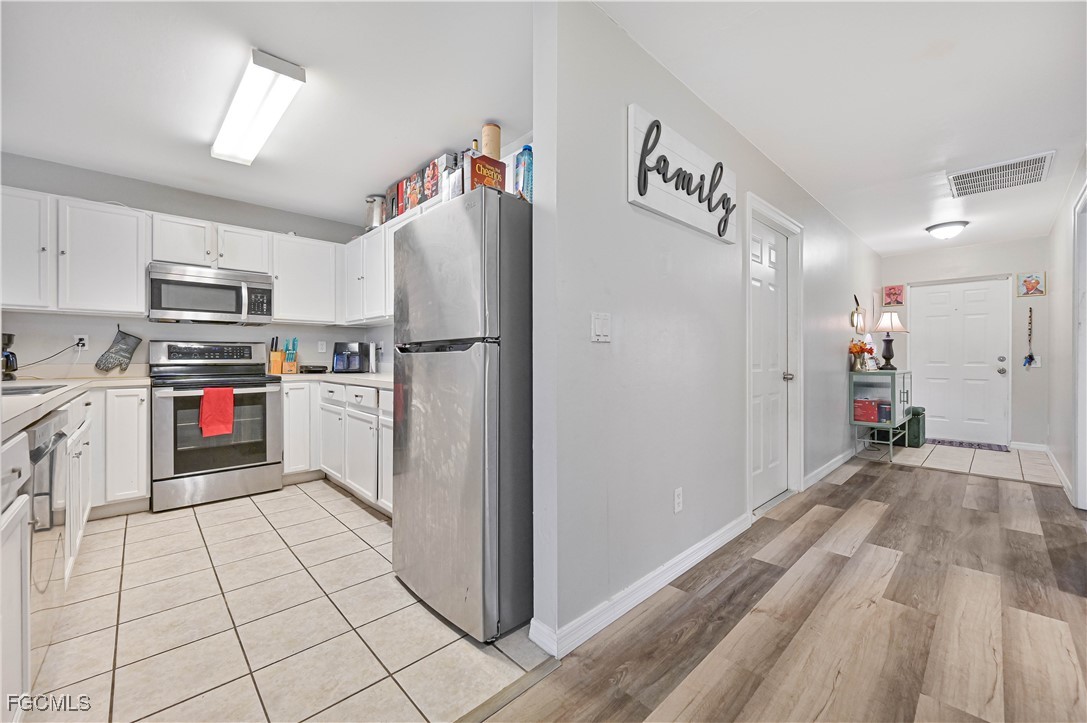721-723 Homer Avenue South, Unit 723 Lehigh Acres, FL 33973 - Photo 26 of 36 a kitchen with a refrigerator a stove top oven and cabinets