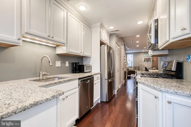a kitchen with granite countertop kitchen island stainless steel appliances a sink a stove a refrigerator and cabinets