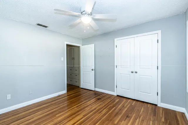 an empty room with wooden floor and a ceiling fan