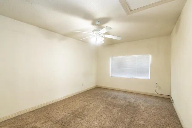an empty room with a window and a ceiling fan