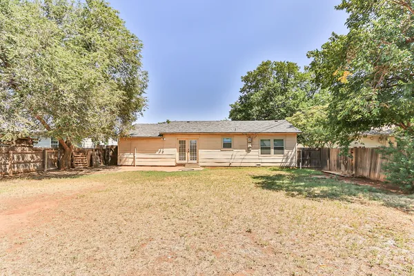 a view of a house with a yard and large trees