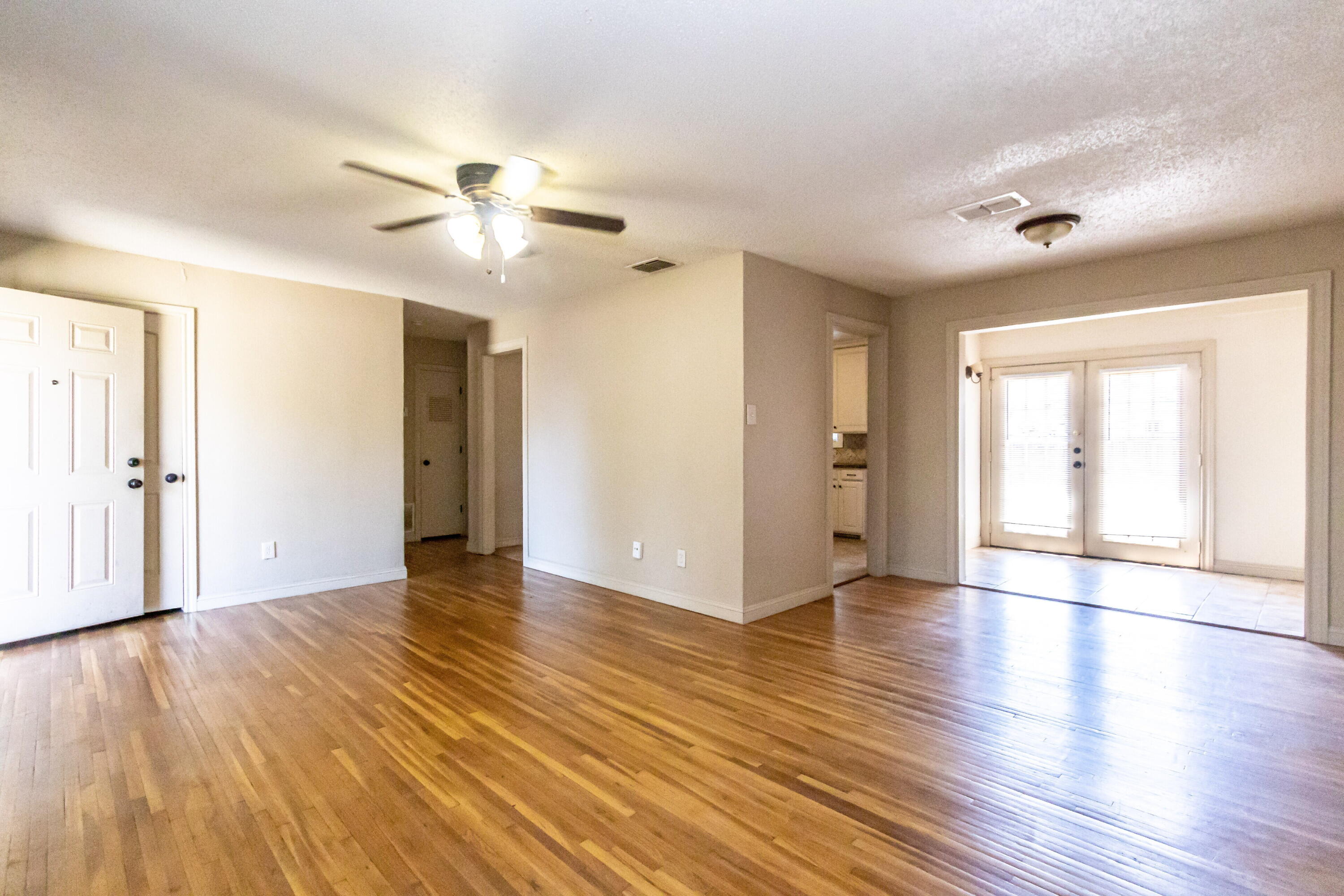 2611 44th Street Lubbock, TX 79413 - Photo 4 of 18 a view of an empty room with wooden floor and a ceiling fan