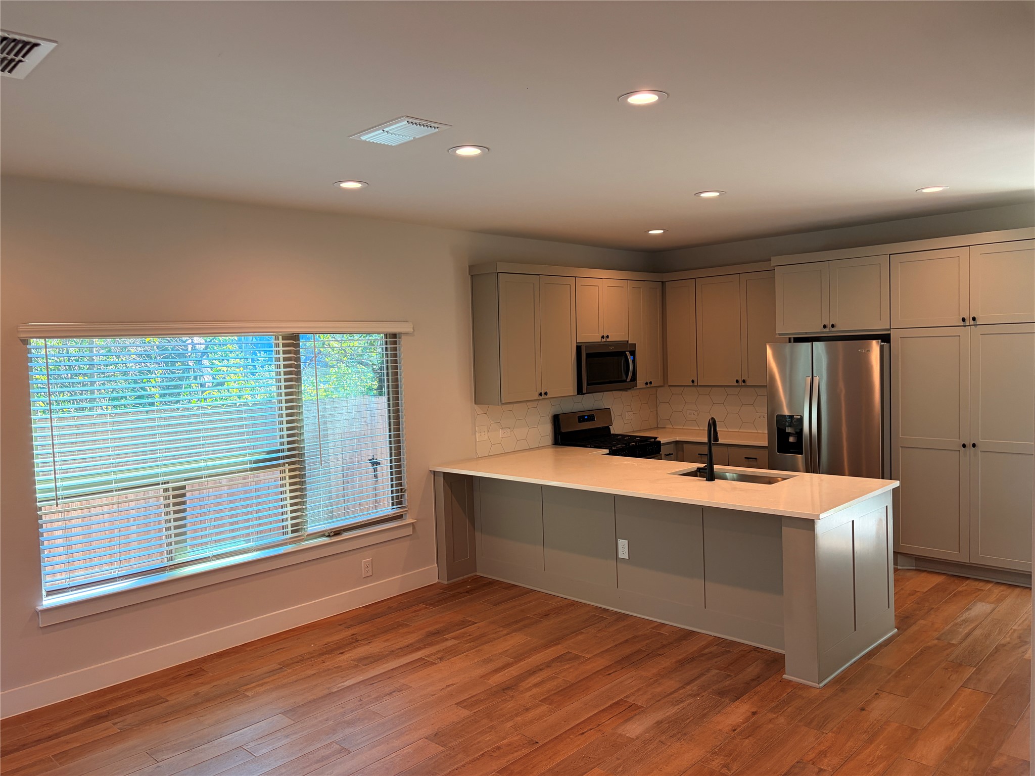 3411 Willow Springs Road, Unit B Austin, TX 78704 - Photo 3 of 8 a large kitchen with stainless steel appliances a large kitchen island a sink wooden floor and a refrigerator