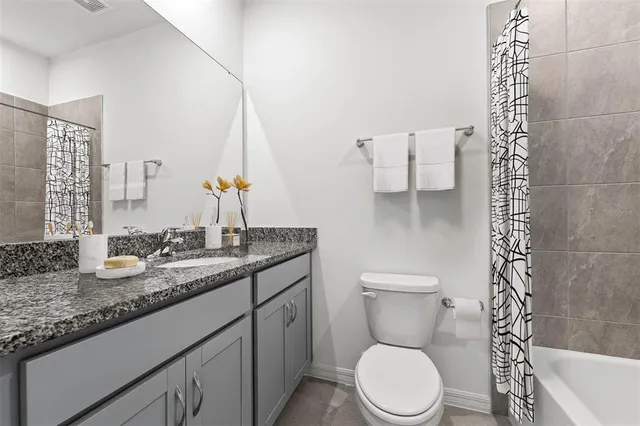 a bathroom with a granite countertop toilet sink and mirror