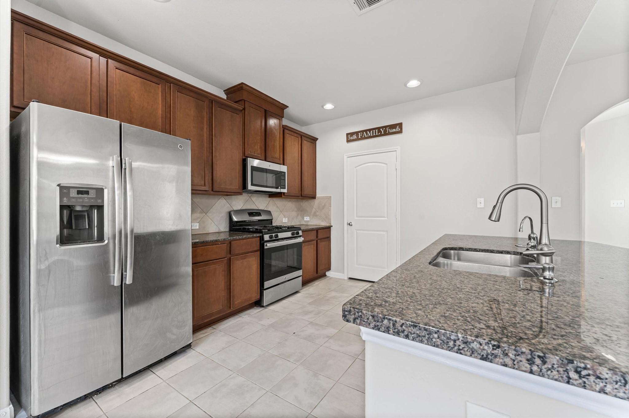 7018 Granite Terrace Lane Houston, TX 77083 - Photo 4 of 18 a kitchen with stainless steel appliances granite countertop a refrigerator a stove and a sink