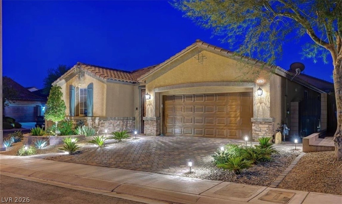 7375 Campbell Ranch Avenue Las Vegas, NV 89179 - Photo 36 of 45 A well-lit exterior showcases a garage with carriage-style doors and desert-friendly landscaping.