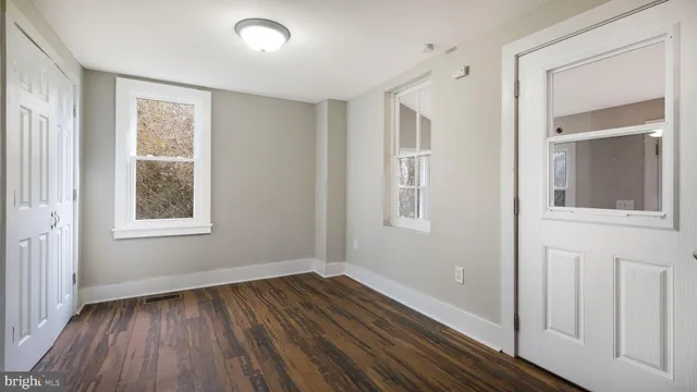 a view of an empty room with wooden floor and a window
