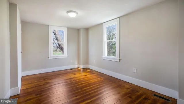 a view of an empty room with window and wooden floor