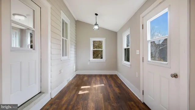 a view of a room with wooden floor ceiling fan and windows