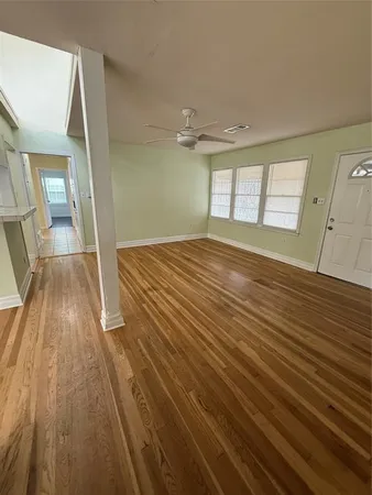 a view of an empty room with a window and wooden floor
