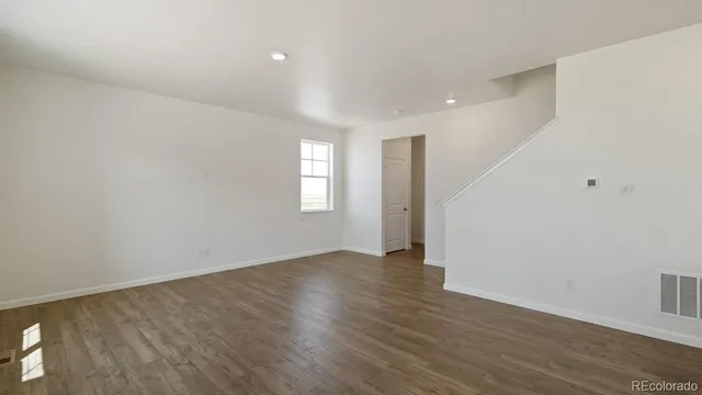 a view of an empty room with wooden floor and window