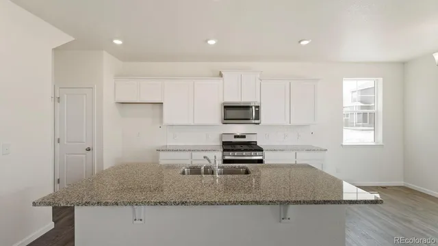 a kitchen with stainless steel appliances granite countertop a sink a stove cabinets and a refrigerator