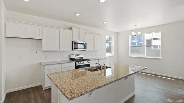 a kitchen with stainless steel appliances granite countertop a sink a stove and white cabinets