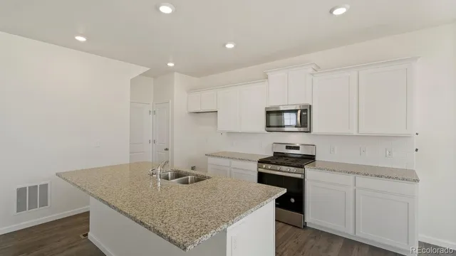 a kitchen with granite countertop a sink stainless steel appliances and white cabinets