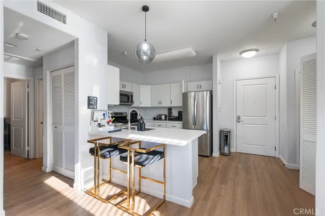 a kitchen with stainless steel appliances a dining table chairs refrigerator and microwave