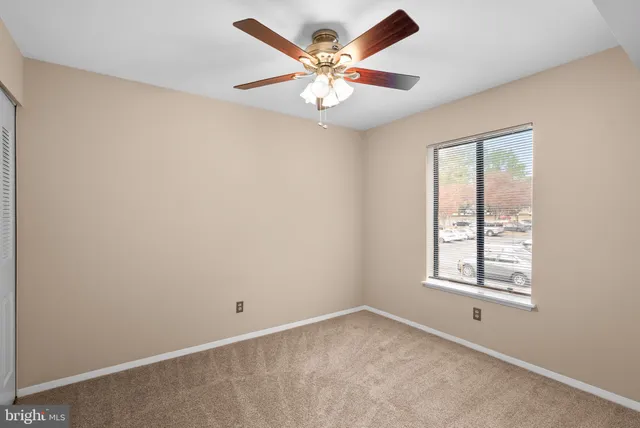 an empty room with window and ceiling fan
