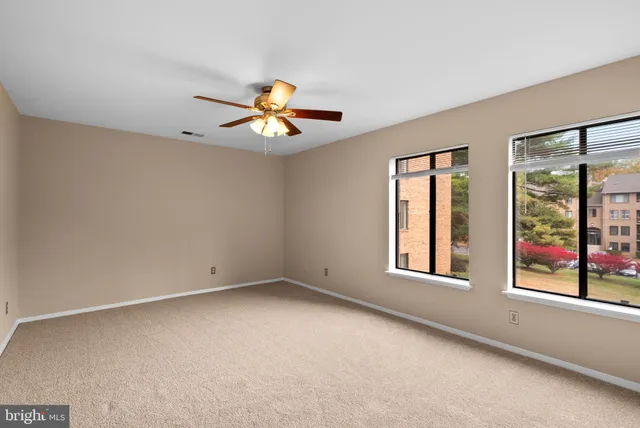 an empty room with windows and chandelier fan