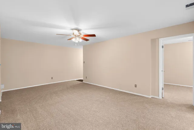 an empty room with a chandelier fan and windows