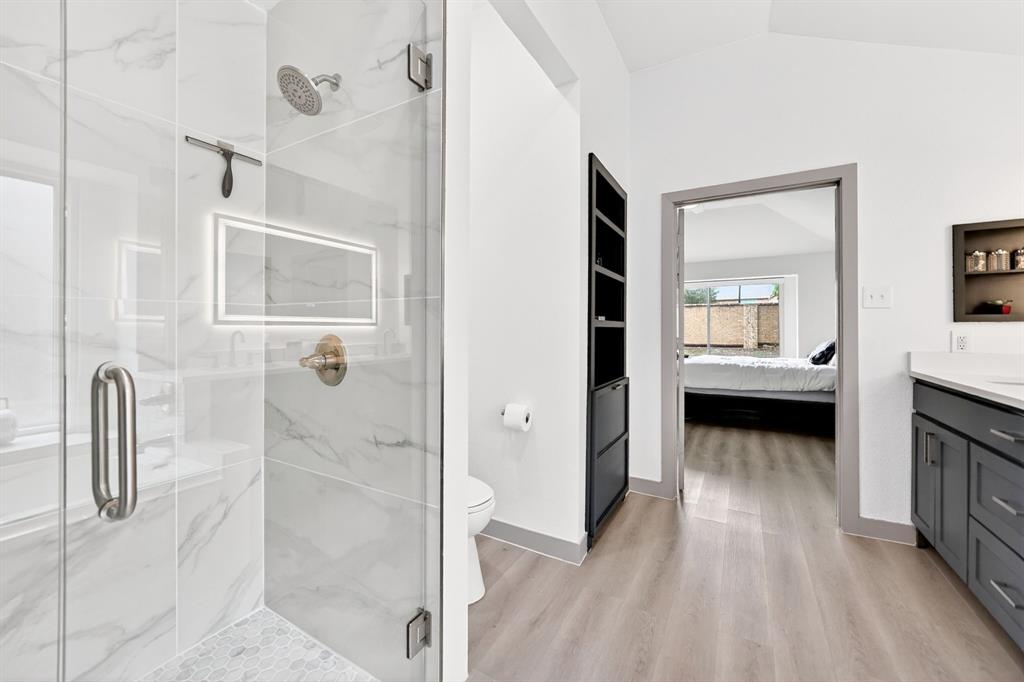 7503 Vista Ridge Lane Sachse, TX 75048 - Photo 21 of 33 Contemporary bathroom featuring a spacious glass-enclosed shower with marble-look tile, a built-in illuminated niche, and a rain shower head
