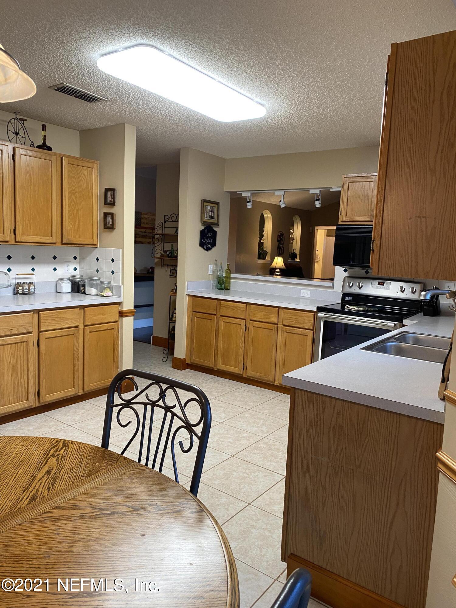 3021 Nautilus Road Middleburg, FL 32068 - Photo 13 of 25 a kitchen with a sink a stove and chairs