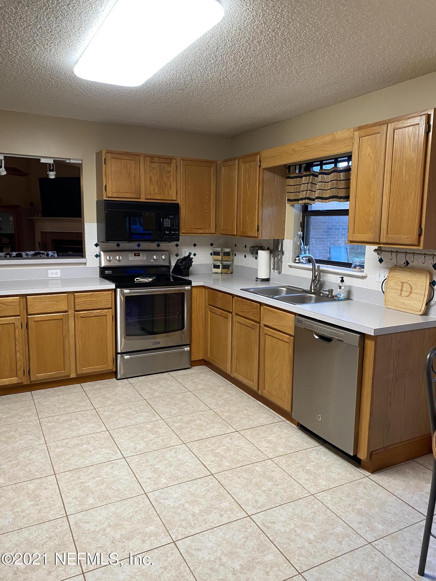 3021 Nautilus Road Middleburg, FL 32068 - Photo 14 of 25 a kitchen with stainless steel appliances granite countertop a sink and cabinets