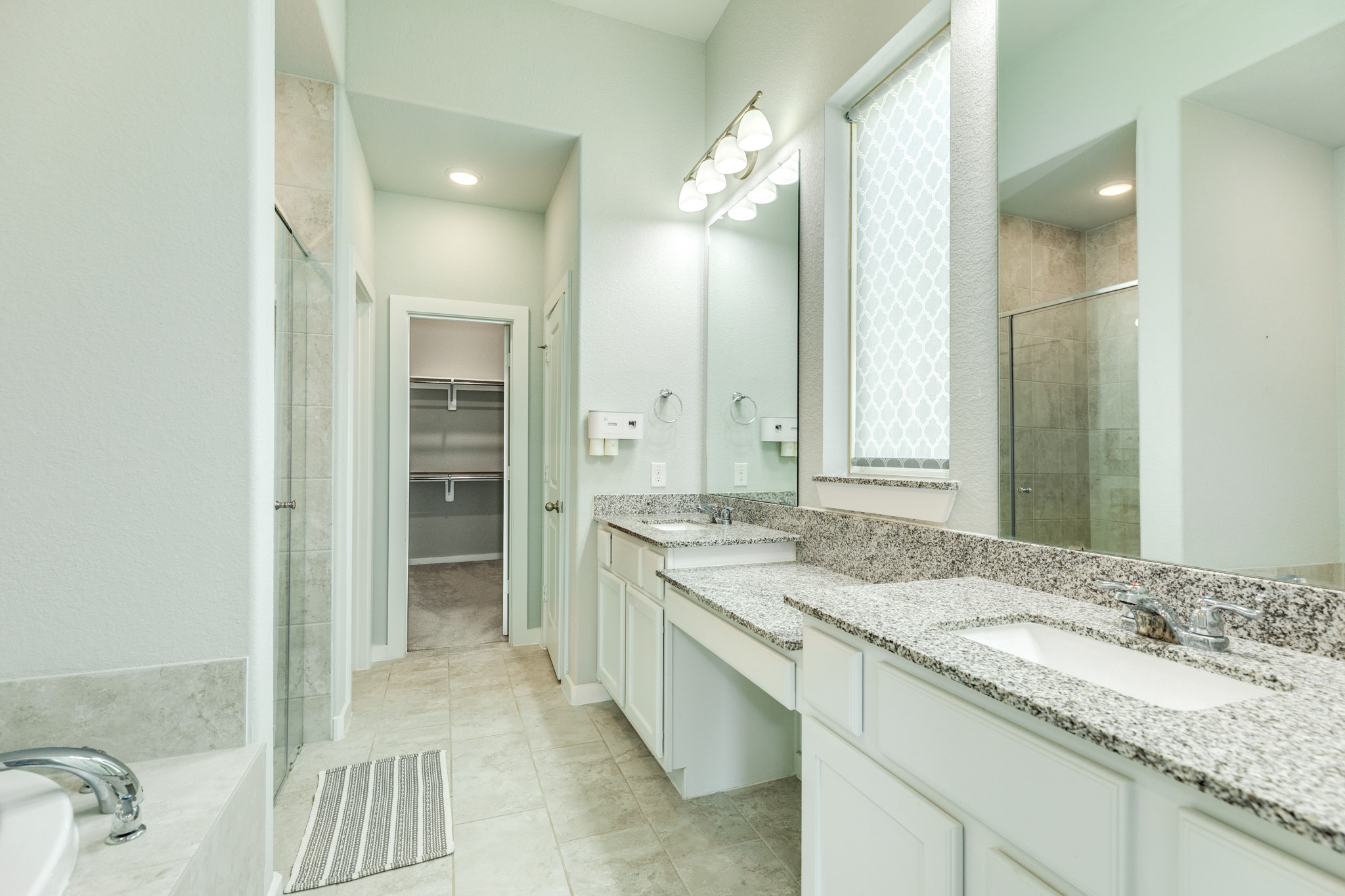 4015 Shackleton Court Iowa Colony, TX 77583 - Photo 19 of 50 Primary bath featuring elegant quartz countertops, a dual-sink vanity, and an expansive oversized mirror complemented by excellent lighting, plus a convenient dedicated dressing area.